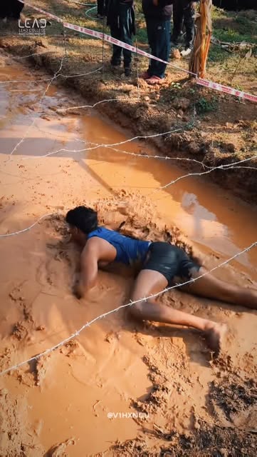Participant crawling through the mud obstacle course